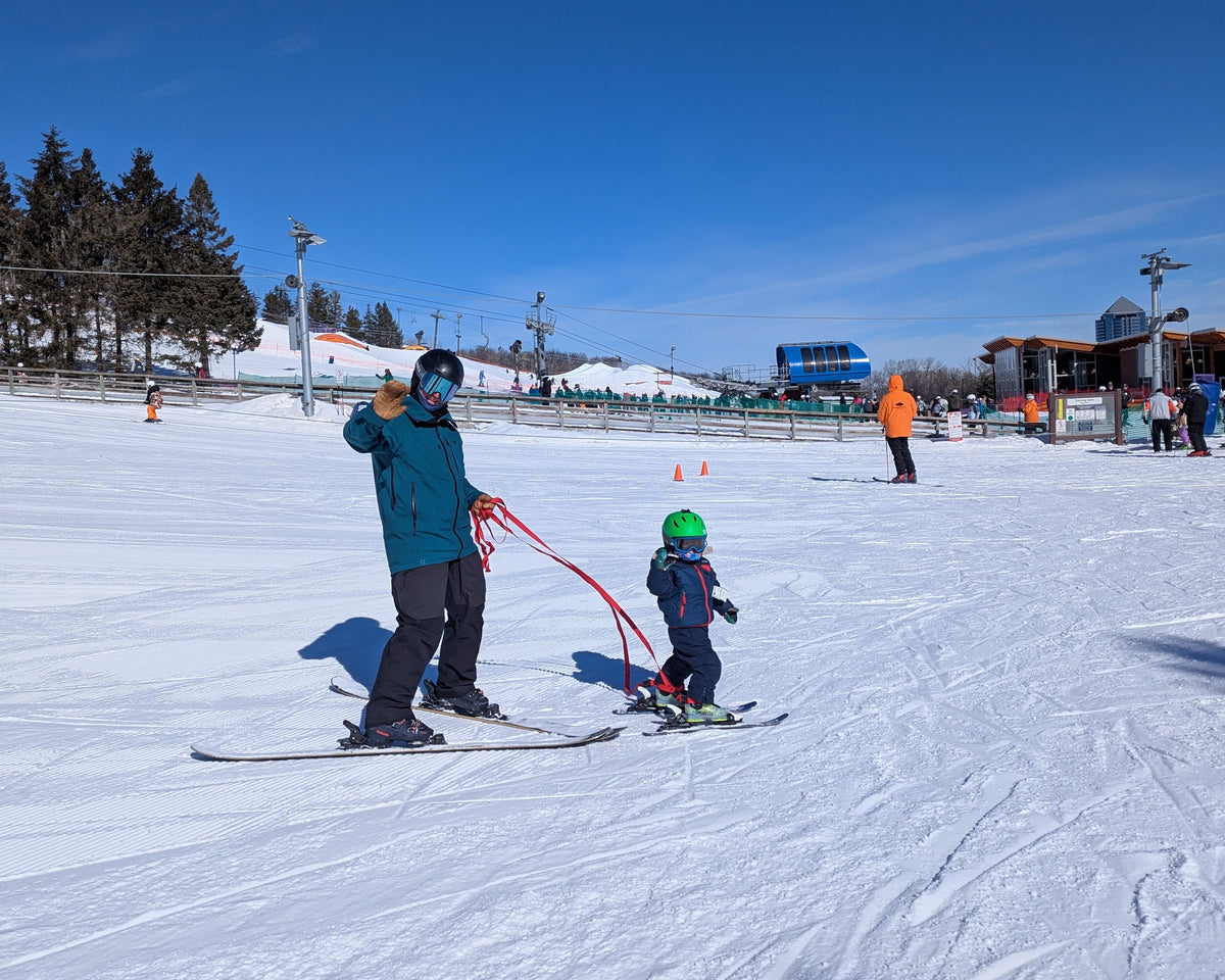 dad and kid waving to camera with snap two ski tethers